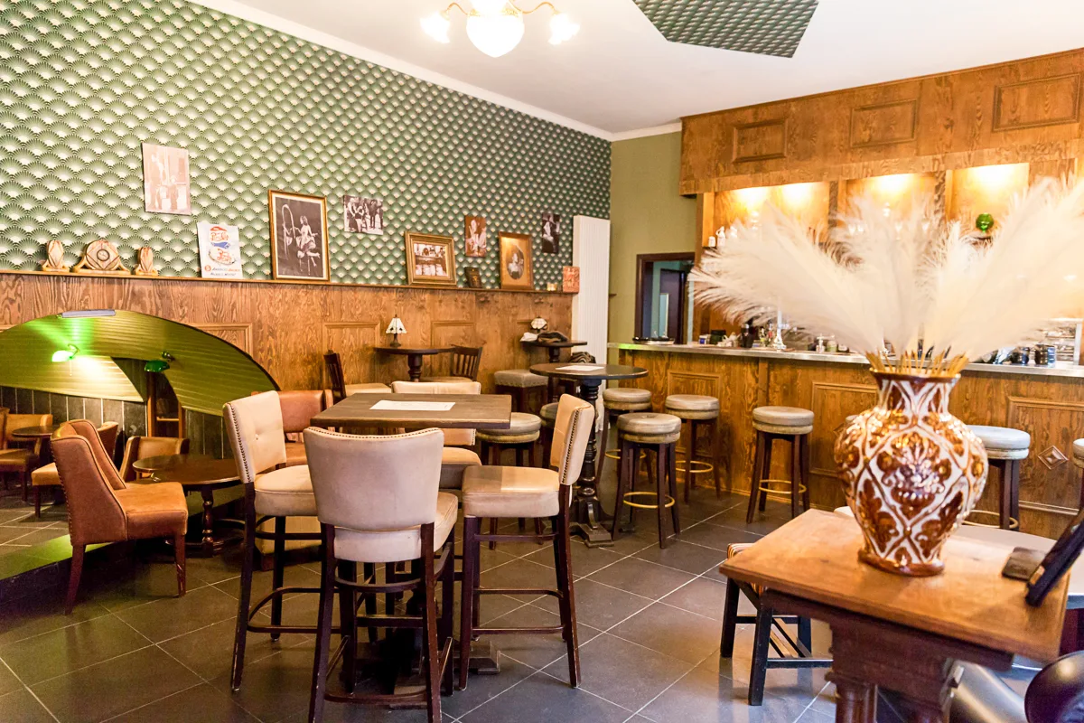 Salle voûtée du speakeasy Green Mill, rue du Palais à Liège : fauteuils en cuir et éclairage vert tamisé.