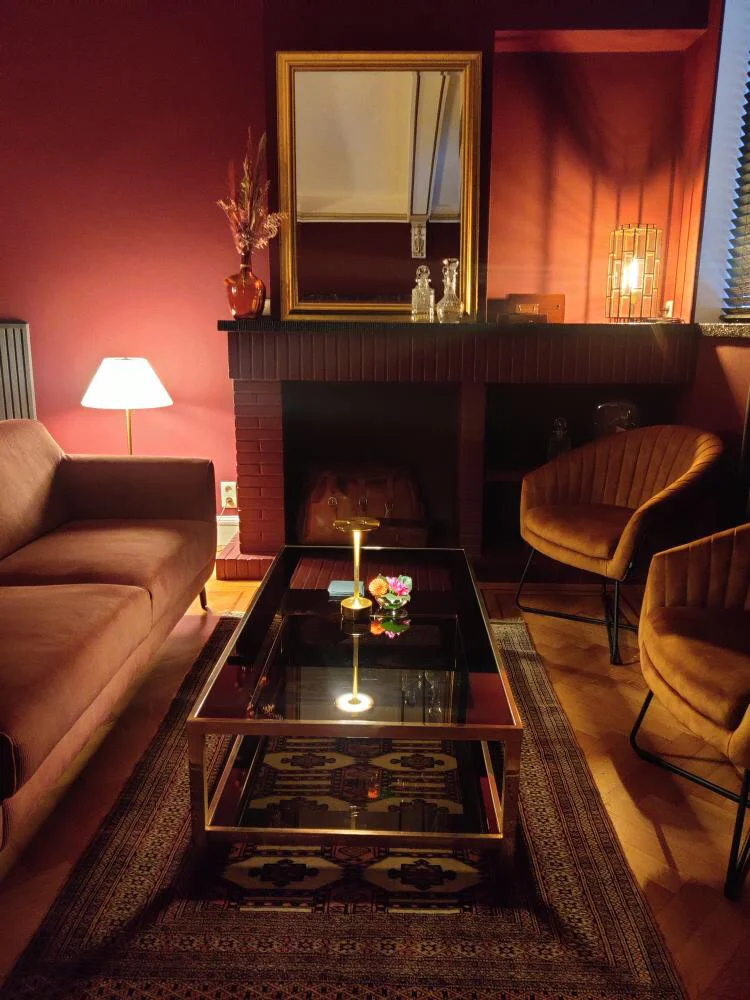 Salon du bar d'hôte Le Cabinet rue Duvivier à Liège : fauteuils en velours, cheminée, table basse et lumière tamisée.