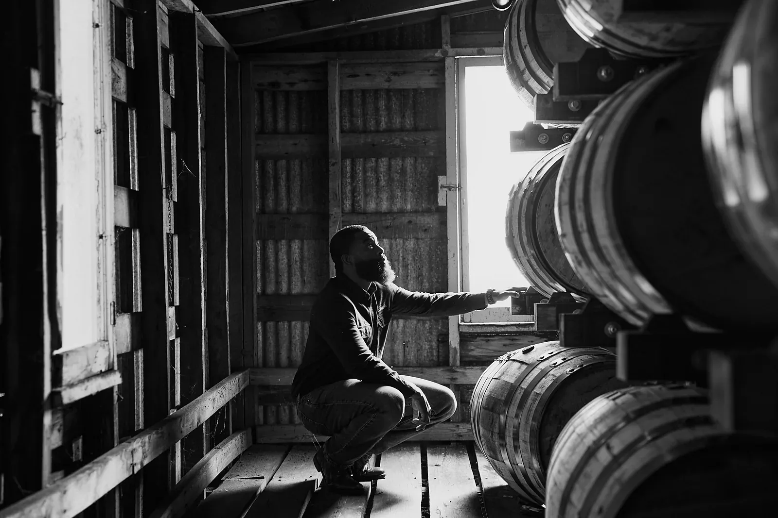 Homme inspectant des fûts de Tennessee whiskey dans un chai de vieillissement de la distillerie Jack Daniel's à Lynchburg.