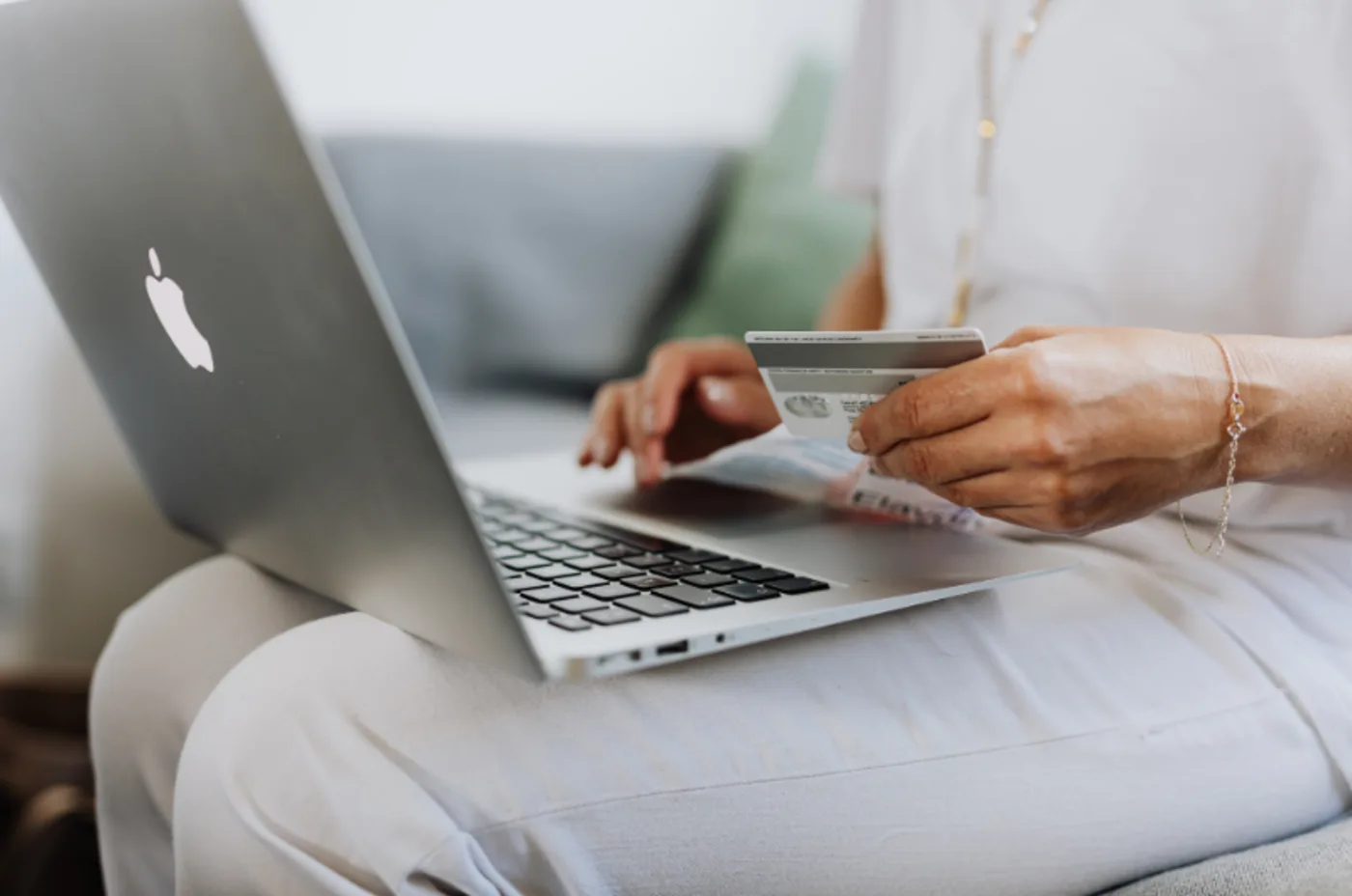 Personne saisissant un numéro de carte bancaire sur un ordinateur portable, illustrant les risques de fraude au paiement.